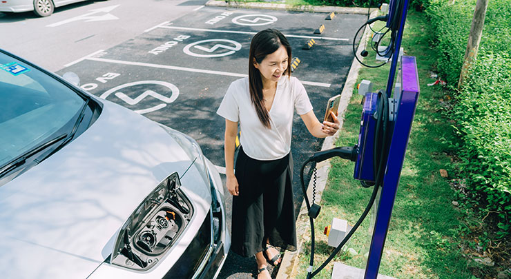 Woman is charging her EV car and taking a photo