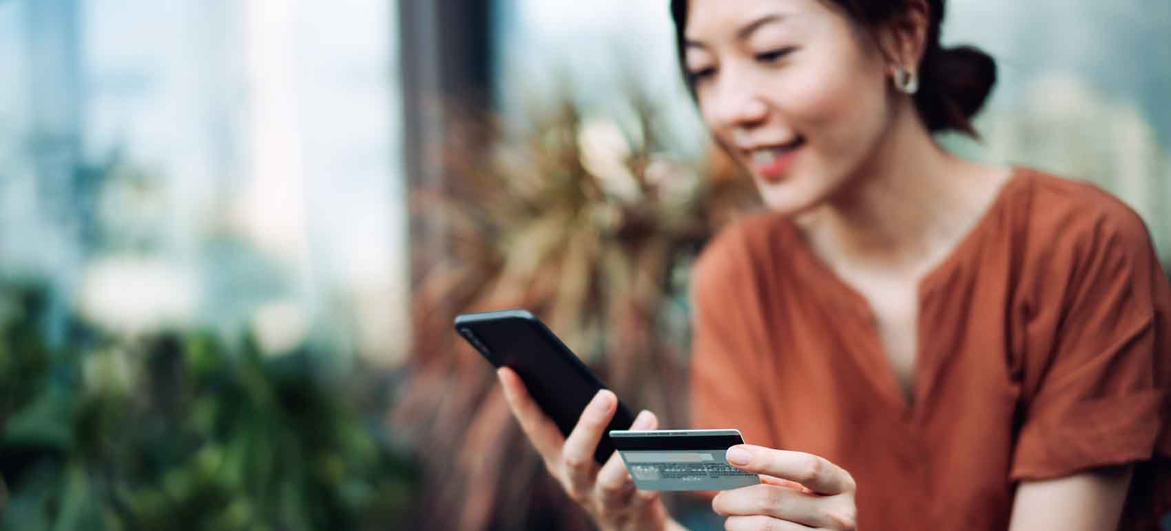 a woman holding her smartphone and credit card