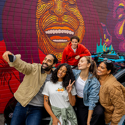 Friends posing with evo and mural art in the background