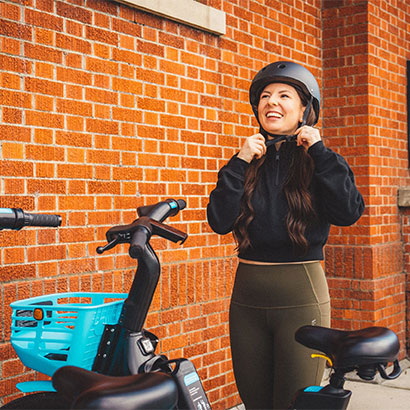 Woman is wearing helmet and setting up for the ride