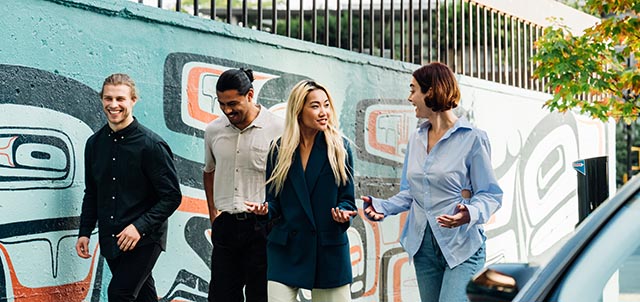 A group of friends walking down a street in front of a mural