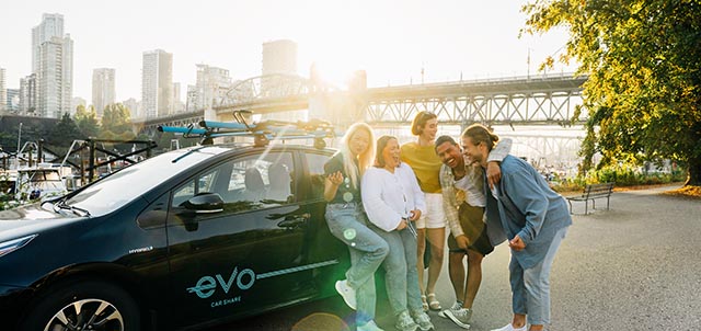 Group of friends standing near a parked Evo at sunset