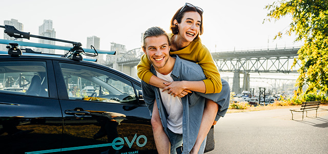 A man giving a woman a piggyback in front of a parked Evo